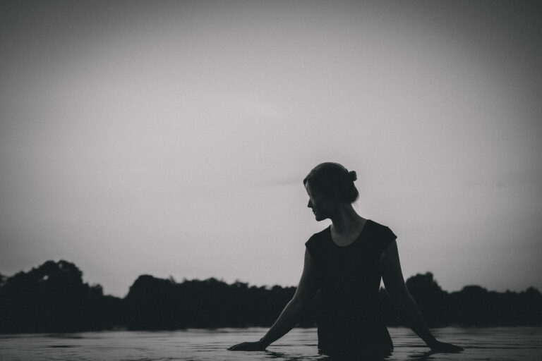 Silhouette einer Frau am Wasser im Gegenlicht, Schwarzweiß