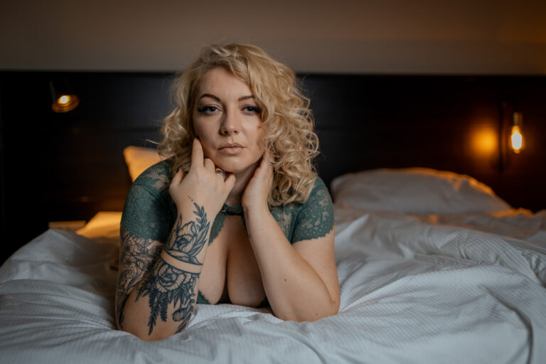 Lächelnde Frau mit Tattoos auf dem Bett