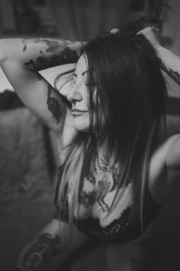 Frau mit Tattoos fährt sich durchs Haar, Schwarzweiß